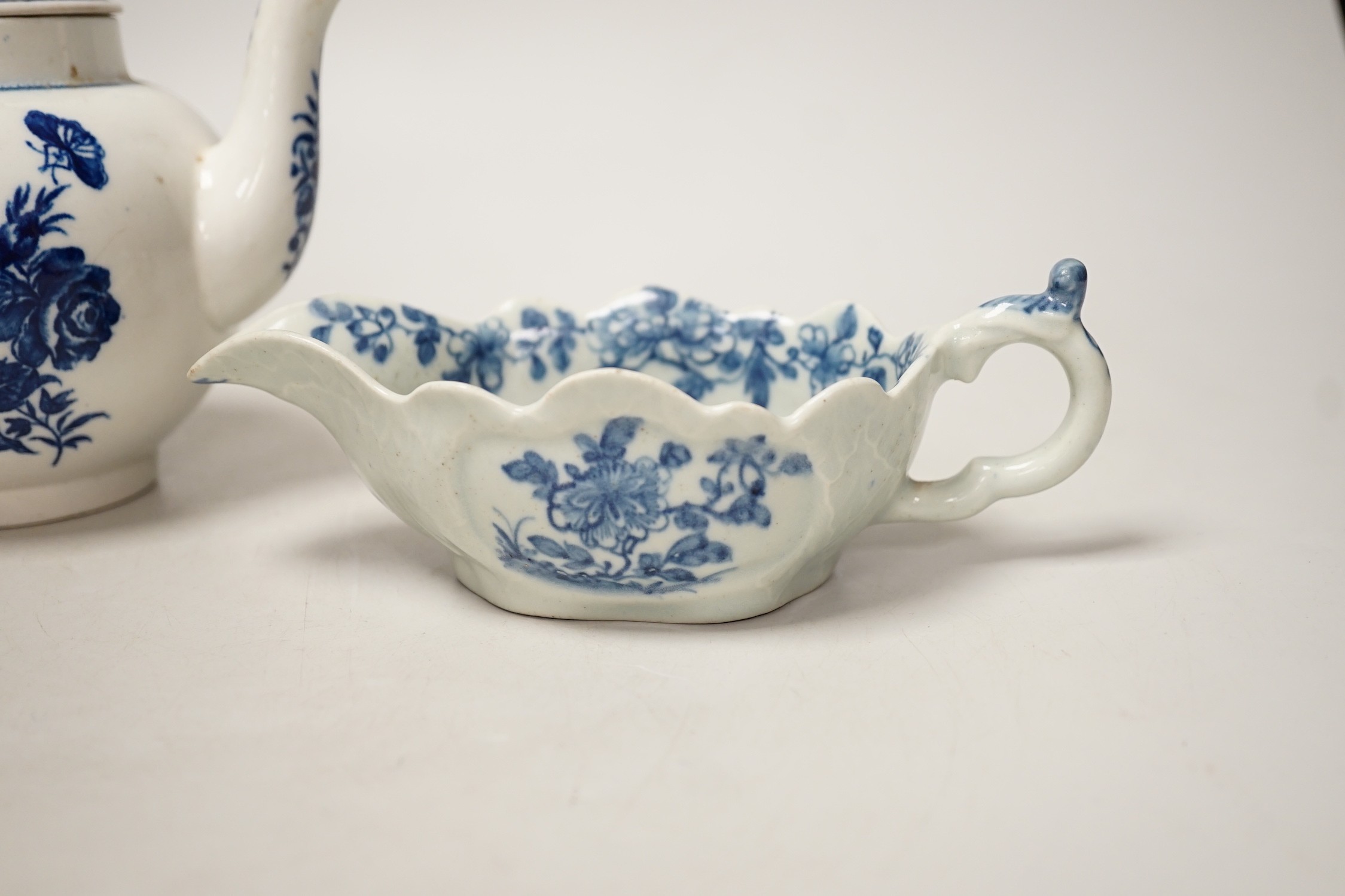 A Liverpool porcelain blue and white sauceboat and a Worcester teapot. Tallest 12cm